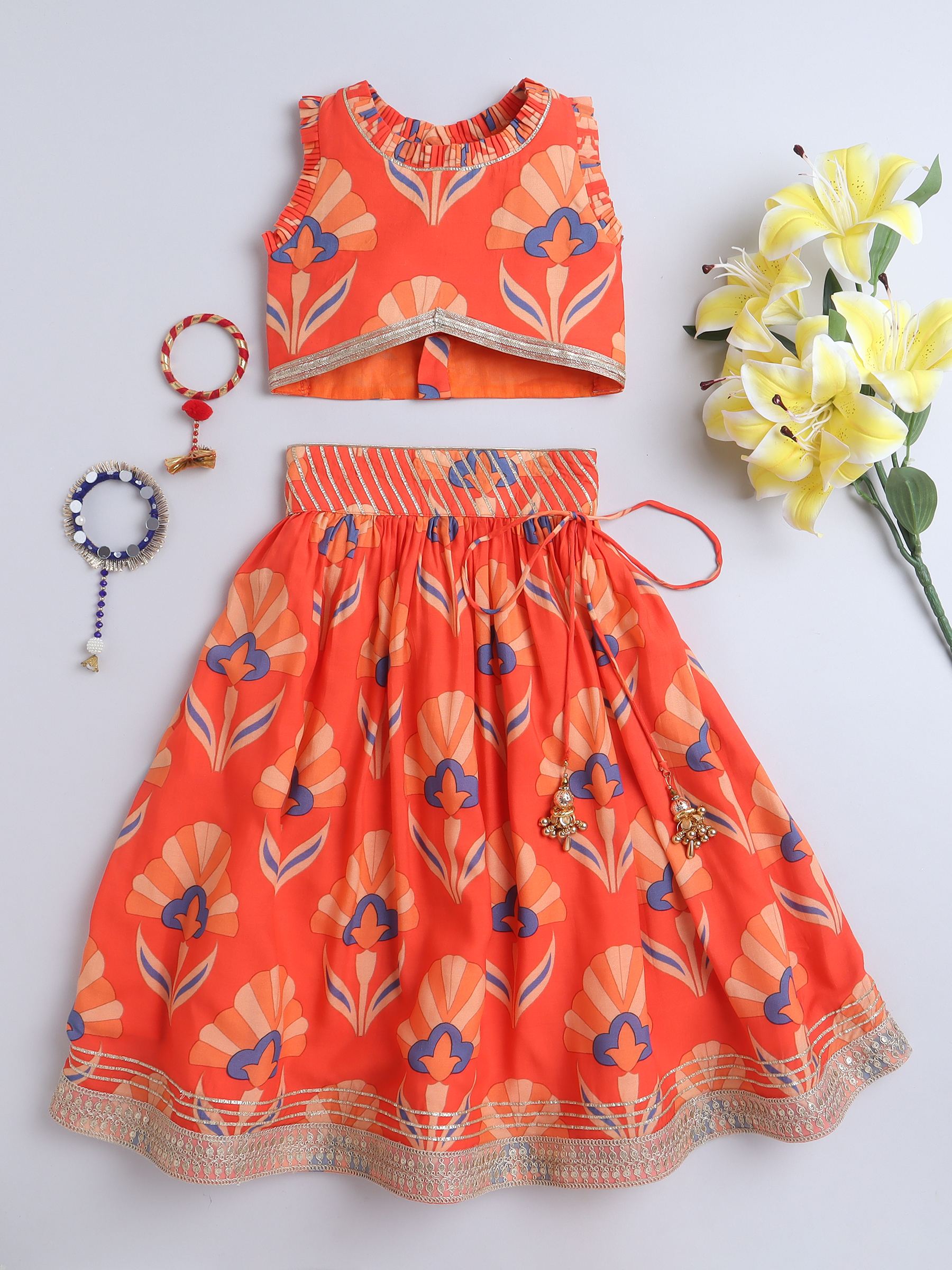 Kids coral orange printed lehenga set with crop top, flared skirt, and tassel detailing
